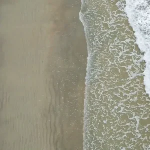 Aerial view of Benaulim Beach in Goa, showcasing the gentle waves lapping onto the golden sandy shore, exemplifying why Goa beaches are famous for their natural beauty and environment